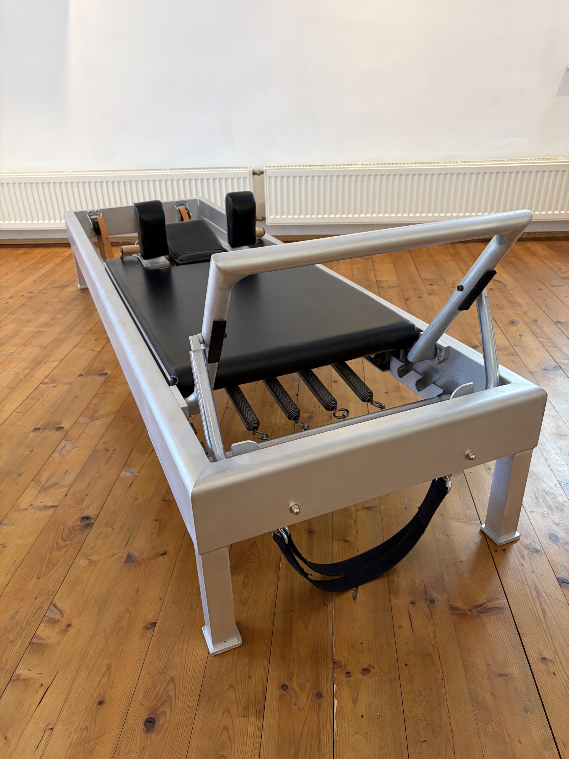 Klassischer Reformer aus Holz im Pilates-Studio.
